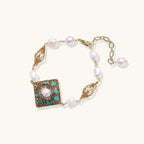 Gold-plated bracelet with baroque centerpiece, turquoise stones, freshwater pearls, and ornate chain links on cream background.