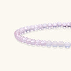Double-wrap lavender beaded bracelet with rose quartz, pearls, gold vermeil charm and pink tassel on white background.