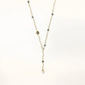 Y-shaped gold-plated necklace with white and gray freshwater pearls on cream background, showing adjustable drop design.