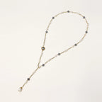 Y-shaped gold-plated necklace with white and gray freshwater pearls on cream background, showing adjustable drop design.