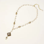 Y-shaped necklace with freshwater pearls, gold filigree stations, and ornate diamond-shaped centerpiece with pearl drop