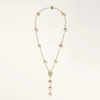 Gold-plated lariat necklace with baroque pearls and textured caps on cream background, showing adjustable Y-shaped design.
