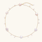 Gold vermeil chain with iridescent star-shaped baroque pearls and small round freshwater pearl drops on cream background.