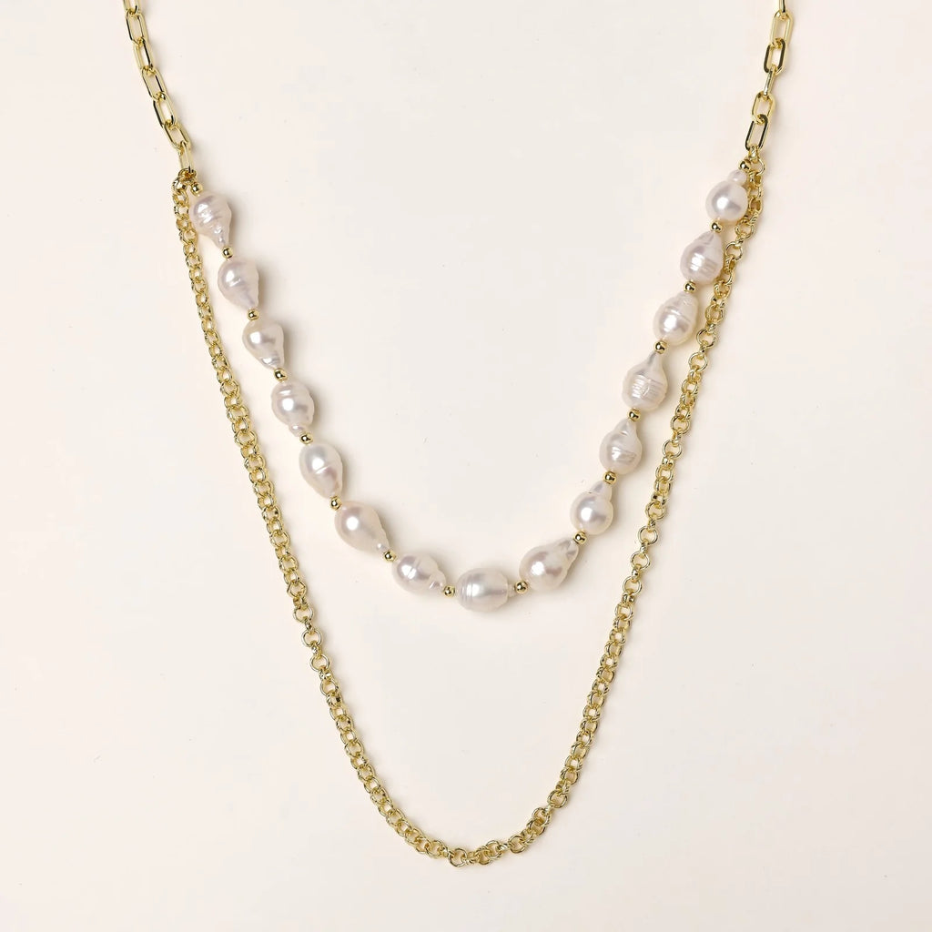 Layered gold chain necklace with organic baroque freshwater pearls and adjustable length on cream background
