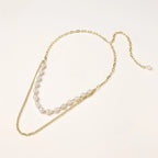 Layered gold chain necklace with organic baroque freshwater pearls and adjustable length on cream background