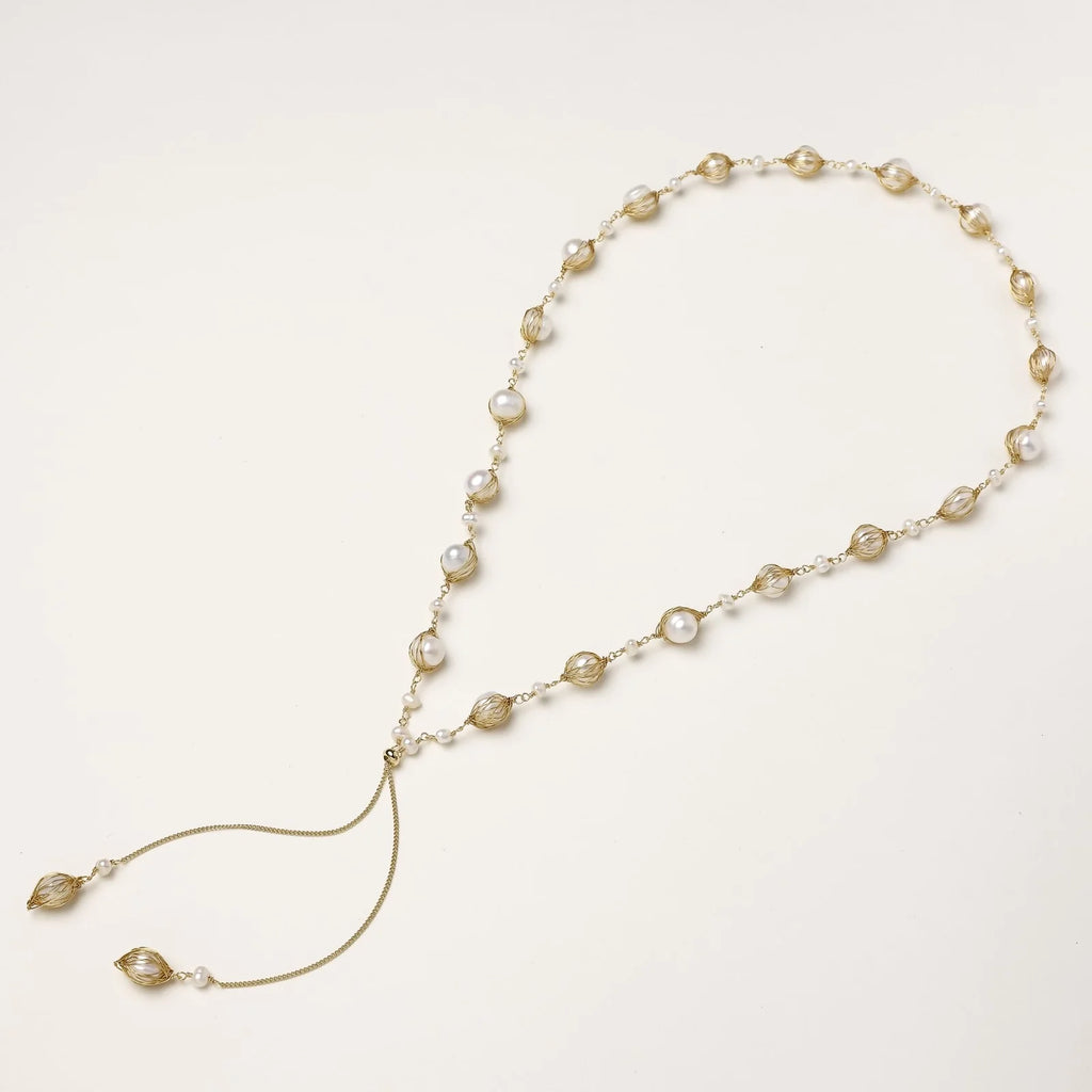 Adjustable gold lariat necklace with freshwater pearls nested in delicate cage settings and Y-shaped tassel drop