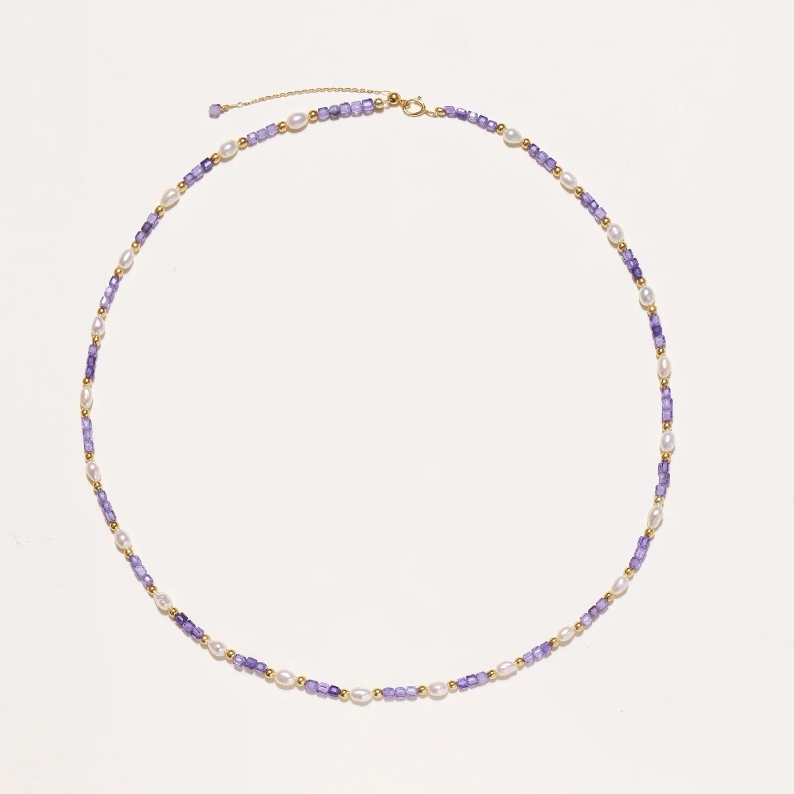 Delicate 18K gold vermeil necklace with alternating lavender zirconia beads and white freshwater pearls on cream background