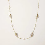 Long gold chain necklace with baroque pearls wrapped in leaf designs and small freshwater pearls spaced along the strand