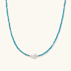 Delicate gold vermeil necklace with teal apatite beads and freshwater pearl on white background.