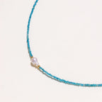 Delicate gold vermeil necklace with teal apatite beads and freshwater pearl on white background.