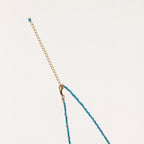 Delicate gold vermeil necklace with teal apatite beads and freshwater pearl on white background.