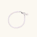 Delicate freshwater pearl bracelet with rhodium-plated silver clasp and single pearl drop charm on cream background
