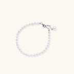 Delicate freshwater pearl bracelet with rhodium-plated silver clasp and single pearl drop charm on cream background