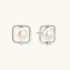 Rhodium-plated silver stud earrings with cushion frame, centered freshwater pearl, and tiny crystal accent