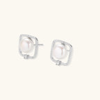 Rhodium-plated silver stud earrings with cushion frame, centered freshwater pearl, and tiny crystal accent