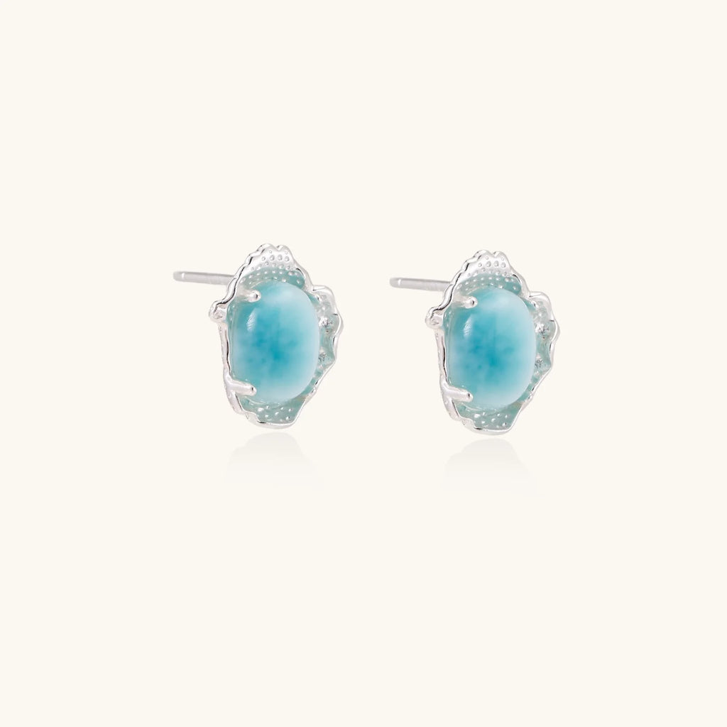 Oval larimar gemstone studs with ornate silver settings showing natural turquoise marbling on cream background
