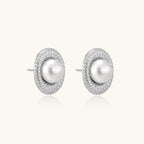 Oval rhodium-plated silver studs featuring freshwater pearls surrounded by pavé crystal halo on white background