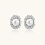 Oval rhodium-plated silver studs featuring freshwater pearls surrounded by pavé crystal halo on white background