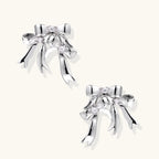 Sculptural bow earrings in polished white gold plate with sparkling zirconia stones and flowing ribbon details