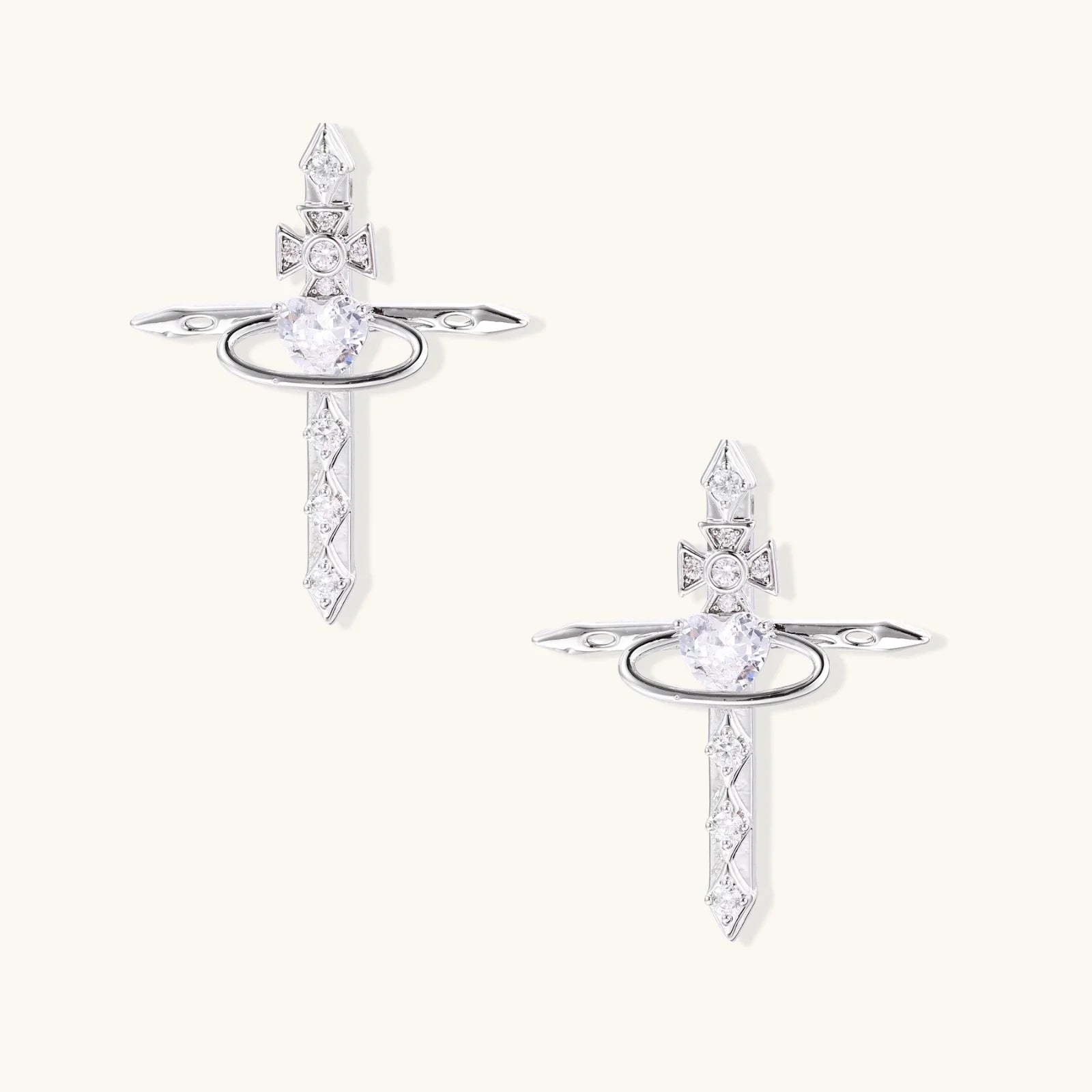 White gold plated cross earrings with orbital ring & zirconia stones on cream background