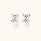 Rhodium-plated silver earrings with twisted X design and freshwater pearl drops on beige background