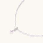 Dainty necklace with lavender crystal beads, freshwater pearls, geometric pendant, and large pearl drop on white background.