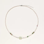 Delicate pearl necklace with pale green serpentine jade centerpiece and colorful agate beads on cream background
