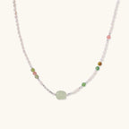 Delicate pearl necklace with pale green serpentine jade centerpiece and colorful agate beads on cream background