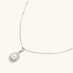 Oval sterling silver pendant with crystal halo surrounding a white freshwater pearl on delicate chain