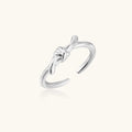 Delicate rhodium-plated silver ring with elegant knot design on cream background, adjustable band style