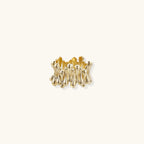 Gold-plated brass ring with sculptural petal-like elements in a wide band design on beige background