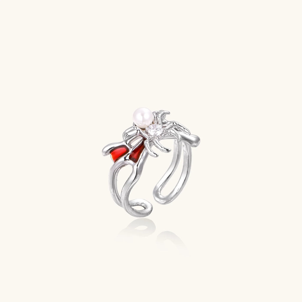 White gold plated spider ring with pearl body, clear zirconia center, and red enamel leg accents on adjustable band