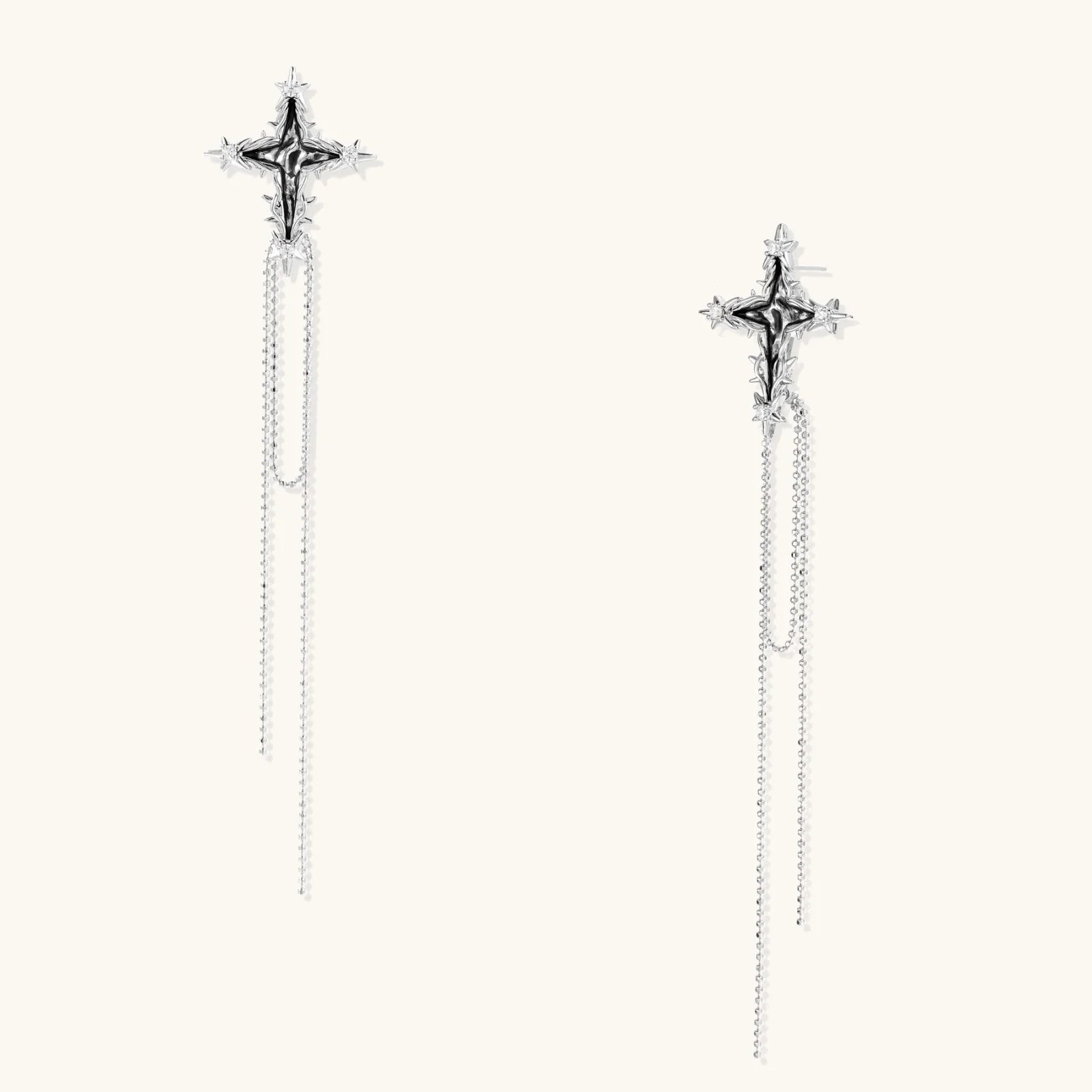 Long silver threader earrings with ornate cross-star design and delicate dual chain tassels on white background