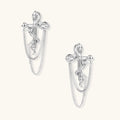 Sculptural white gold bow earrings with cascading chain details on neutral background