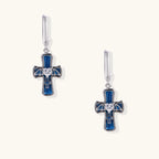 Silver huggie earrings with blue enamel cross charms featuring bat wings and heart-shaped crystal center