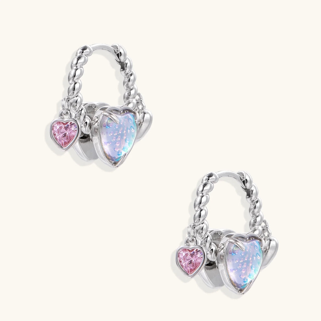 Silver chain hoop earrings with iridescent opal heart charms and pink zirconia accents on white background