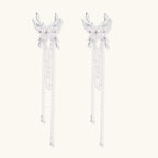 Elegant chandelier earrings with phoenix wing design, white pearls, and cascading silver chains on cream background