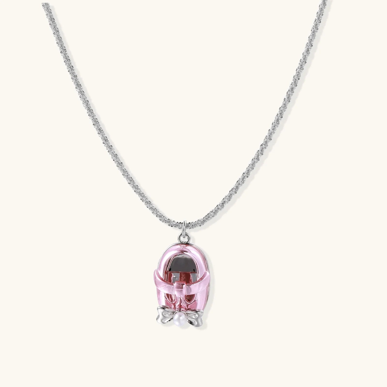 Translucent pink skull pendant with silver bow detail on delicate white gold plated chain against cream background