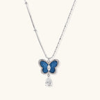 Silver-toned butterfly pendant with blue denim fabric inlay and teardrop crystal on dual-chain necklace