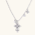 Ornate white gold-plated cross pendant with zirconia stones and pearl accents on adjustable silver chain against cream background