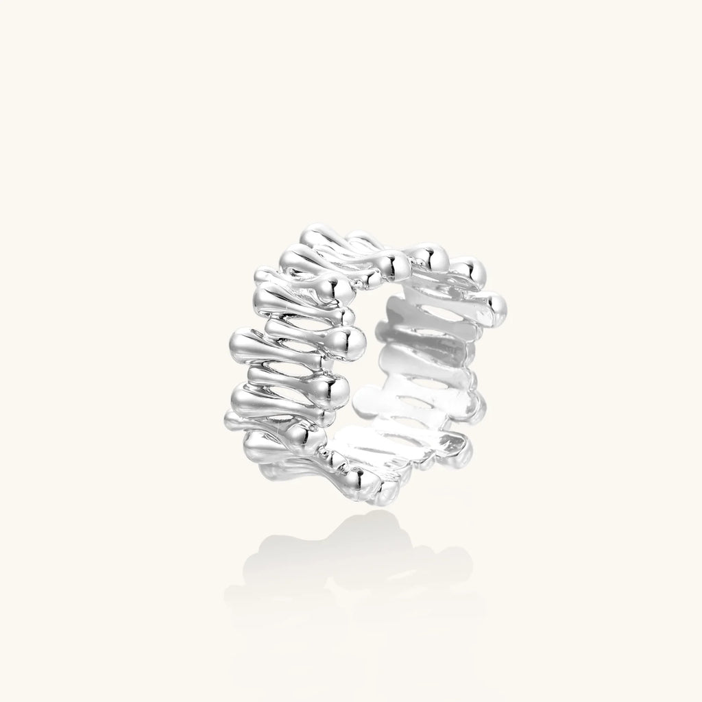 Wide band ring with sculptural wave ripples in polished white gold plated eco-brass on cream background