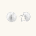 Brushed sterling silver half-dome clip-on earrings with textured surface against cream background