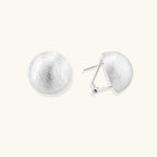 Brushed sterling silver half-dome clip-on earrings with textured surface against cream background