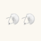 Brushed sterling silver half-dome clip-on earrings with textured surface against cream background