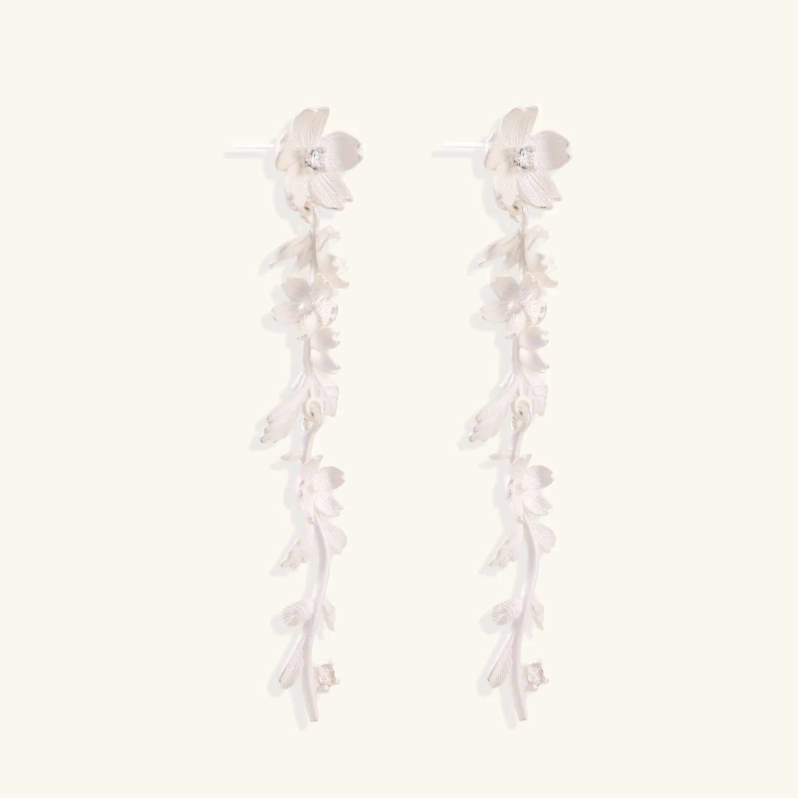 Long sterling silver drop earrings with delicate floral vine design and crystal accents on white background