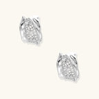 Close-up of sculptural hoop earrings with lattice center band and smooth twisted edges in white gold-plated brass with zirconia