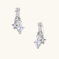 White gold-plated huggie earrings with geometric emerald-cut zirconia clusters in starburst formation on beige background
