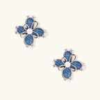 Blue denim fabric flower studs with white gold plated petals, pearl center, and zirconia accents on white background
