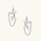 Silver star studs with crescent moon cutouts and zirconia stones connected by delicate chains on white background