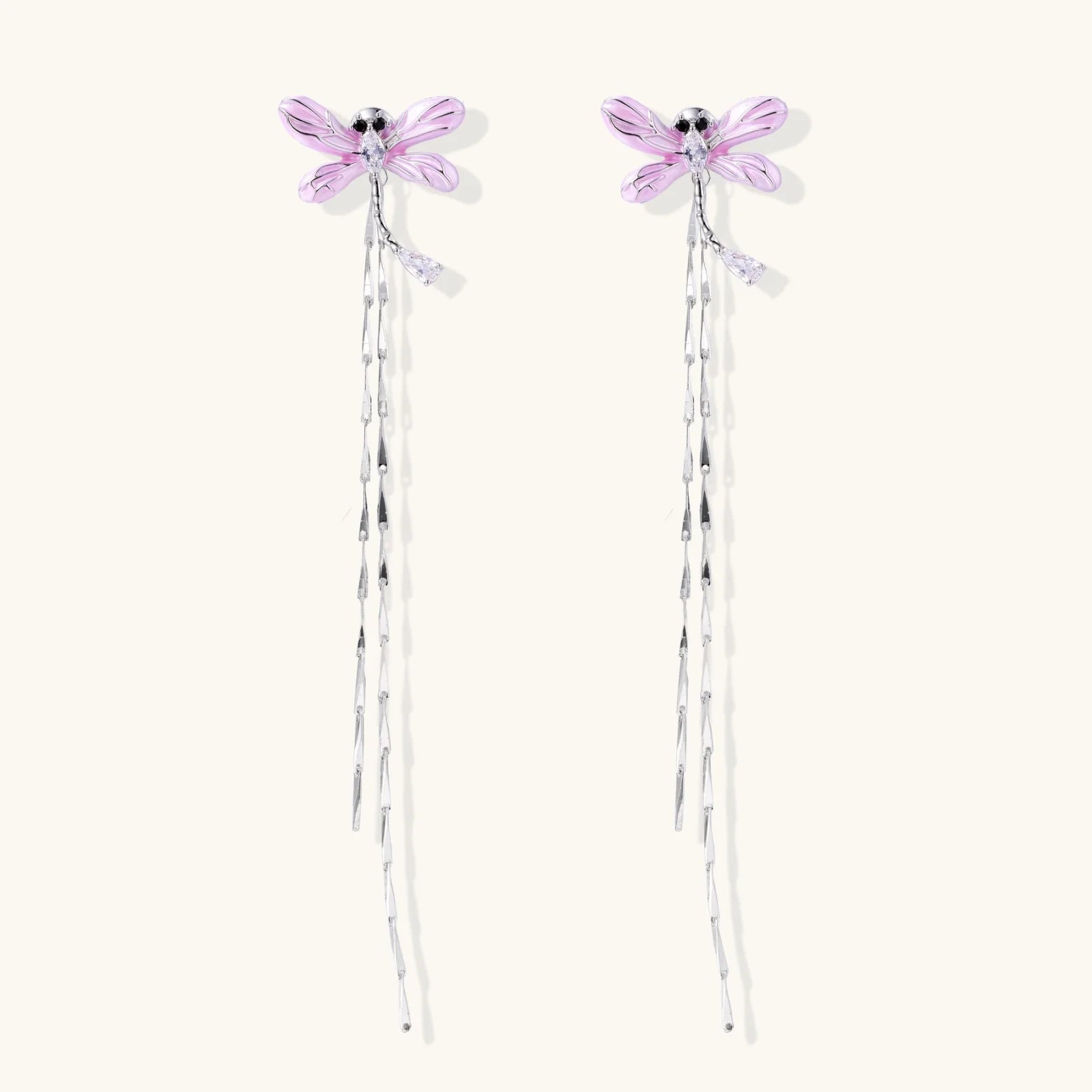 Long drop earrings with translucent lavender enamel dragonfly wings and white gold plated segmented bodies on white background